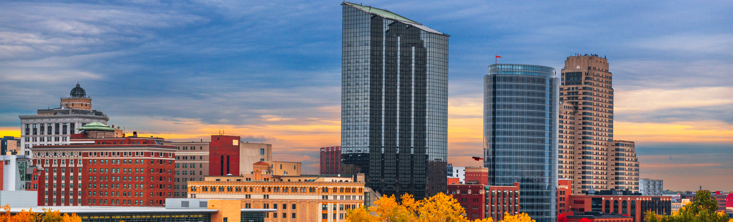 Cityscape of Grand Rapids, MI, showcasing modern and historic buildings against a sunset sky, representing the local community context for retirement planning services.