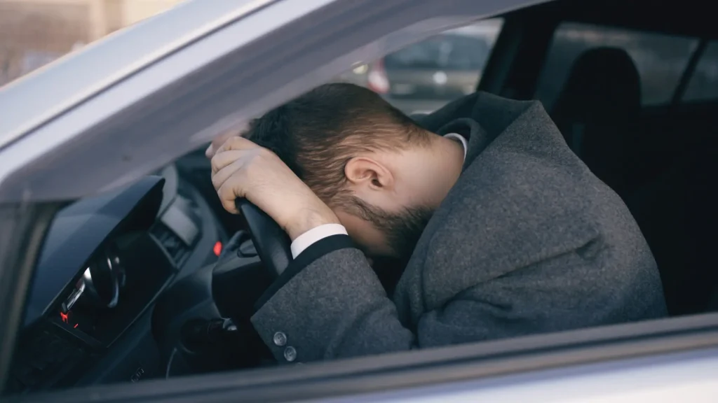 Photo of person in car frustrated laying head on wheel